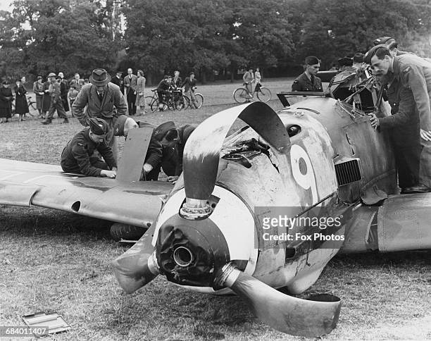 Royal Air Force Maintenance Unit personnel examine the wreckage of a Messerschmitt BF 109E-1 of Jagdgeschwader 7 fighter wing of the German Luftwaffe...