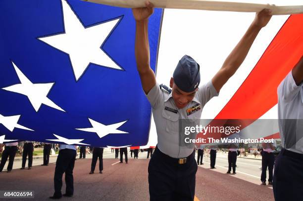 Tyler Whitsett, a First Lieutenant cadet with the Civil Air Patrol United States Air Force Auxiliary helps to hold up a large American flag prior to...