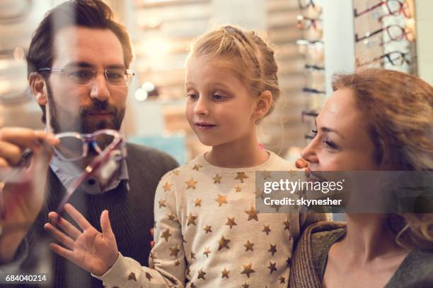 stockent les heureux parents de choisir des lunettes pour leur petite fille à l’opticien. - famille avec des lunettes de vue photos et images de collection