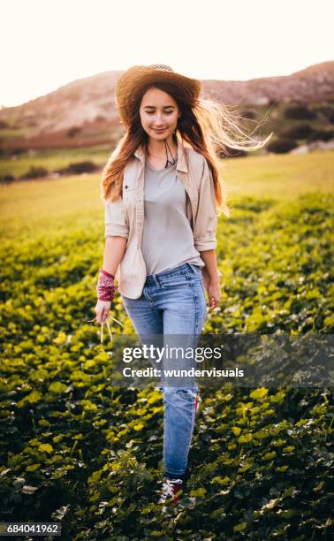 farm girl walking alone in a green field - girl and blond hair and cowboy hat stock pictures, royalty-free photos & images