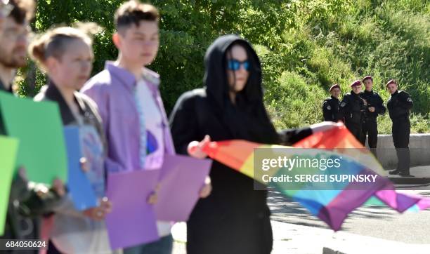 Police officers stand guard next to Ukrainian LGBT activists to prevent attacks from far-right militants during an action in Kiev marking the...