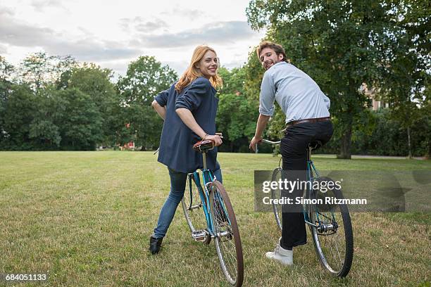smiling young couple with bicycles in park - fahrrad grün stock-fotos und bilder
