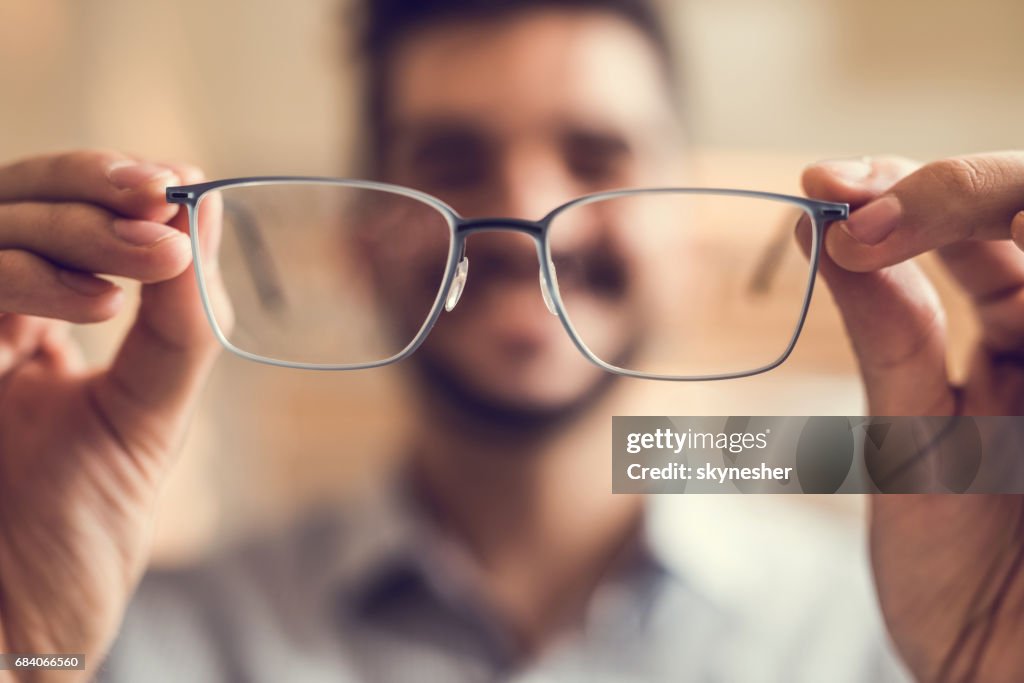 Cerca de un hombre que sostiene las lentes antes de tratar.