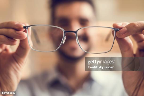 primo tempo di un uomo che tiene gli occhiali prima di provarli. - occhiali da lettura foto e immagini stock
