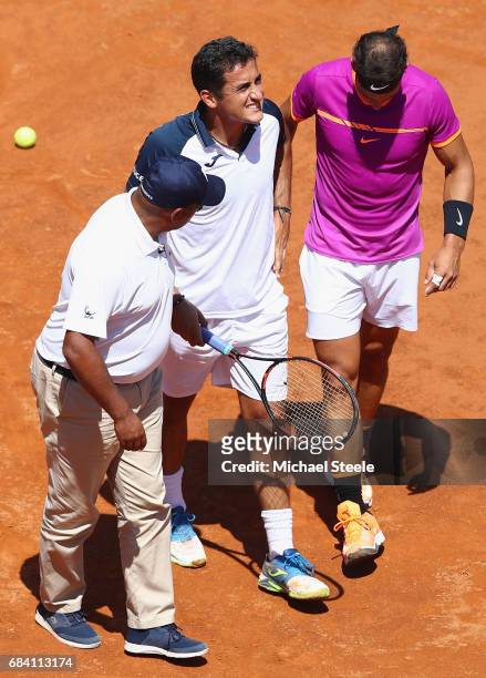 Nicolas Almagro of Spain is helped off court by Rafael Nadal of Spain and umpire Carlos Bernardes after retiring at 0-3 in the opening set on Day...