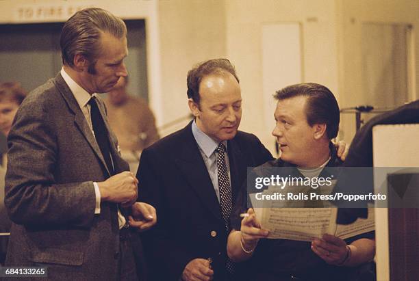 English singer Matt Monro pictured right in a recording studio with English record producer George Martin and an unidentified studio arranger during...
