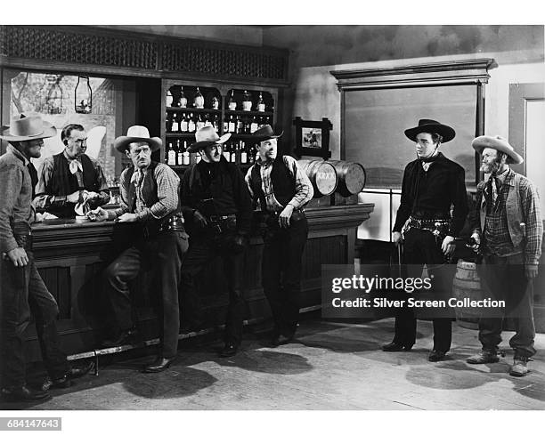 Actors Al St. John as Fuzzy and Lash La Rue as Cheyenne in the western film 'Pioneer Justice', 1947. They are confronting Bill Judd and his gang.