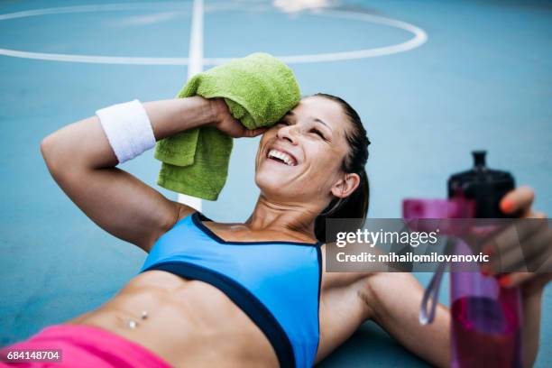 a woman wipes the sweat off her face - finishing workout stock pictures, royalty-free photos & images