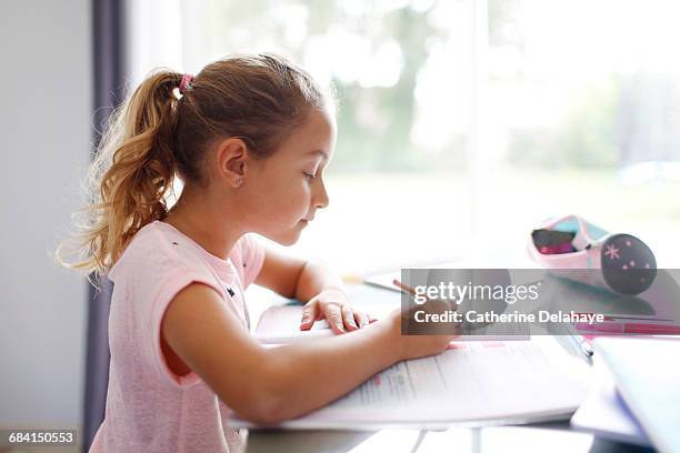 a 7 years old girl doing her homework - 8 years stock-fotos und bilder