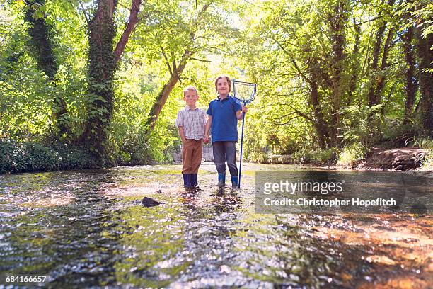 two young brothers standing in a shallow river - boy river looking at camera stock pictures, royalty-free photos & images