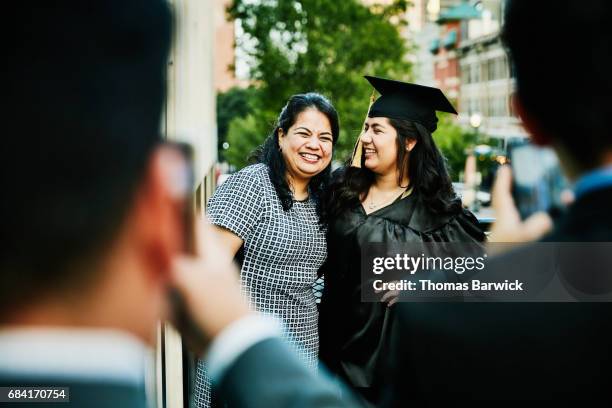 laughing mother and daughter posing for graduation photos during dinner on restaurant deck - abschlussfeier stock-fotos und bilder
