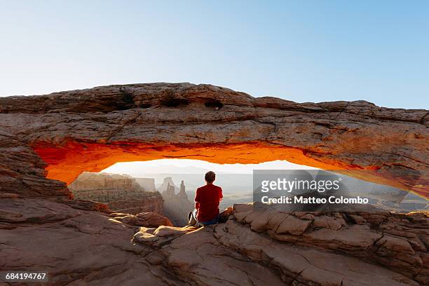 man enjoying sunrise at mesa arch, canyonlands - imponente fotografías e imágenes de stock