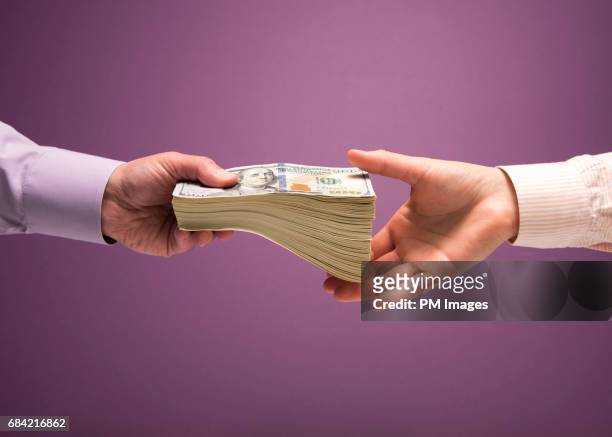 man and woman's hands handing pile of cash - geven stockfoto's en -beelden