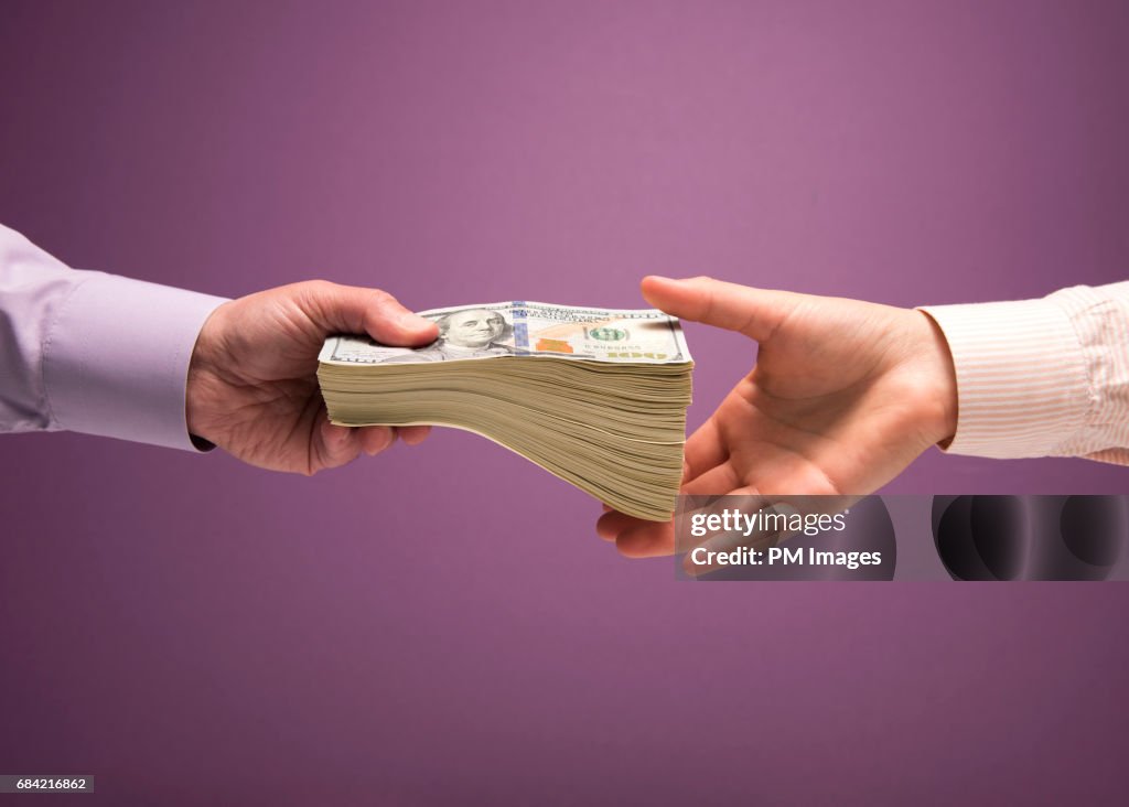 Man and woman's hands handing pile of cash
