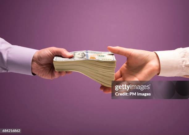 man and woman's hands handing pile of cash - distribution stock pictures, royalty-free photos & images