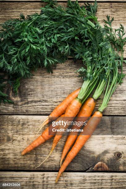 fresh organic carrots over wooden background - möhre stock-fotos und bilder