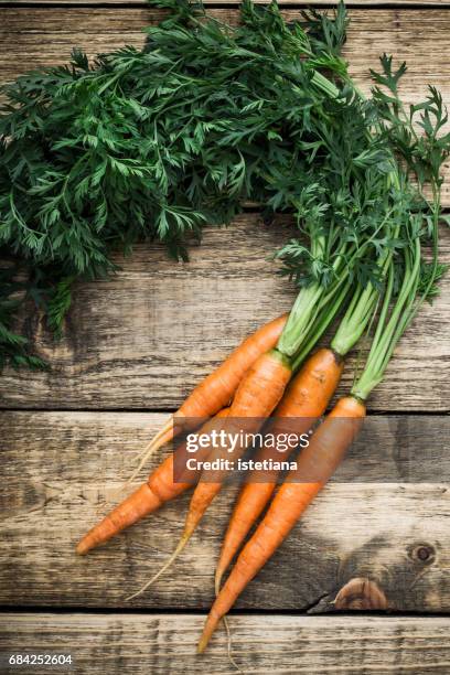 fresh organic carrots over wooden background - carrot fotografías e imágenes de stock