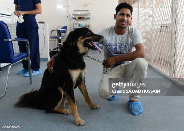 In this photograph taken on April 24 Indian dog owner Sunil Kumar and his dog Kuku pose for a photogrpah after Kuku underwent a blood test at the...