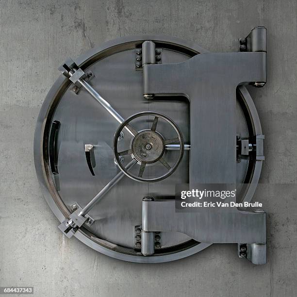 bank vault door on cement wall - eric van den brulle stock-fotos und bilder