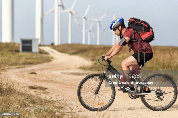radsportler, die vor wind-turbine-bauernhof - bike headset stock-fotos und bilder