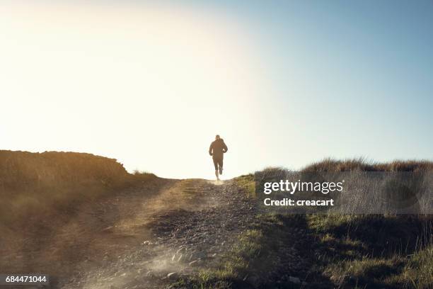 man fell running in remote hillside location. - man escaping stock pictures, royalty-free photos & images