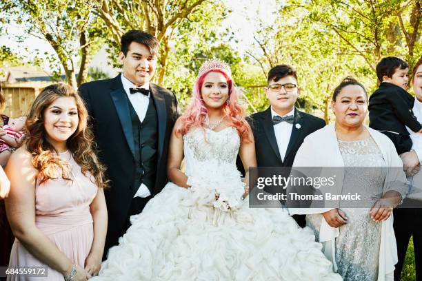 young woman dressed in quinceanera gown standing in backyard surrounded by family - boy wearing dress stockfoto's en -beelden