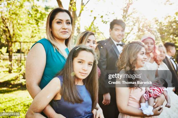 mother embracing young daughter while standing with family in backyard before quinceanera - older woman birthday stock pictures, royalty-free photos & images