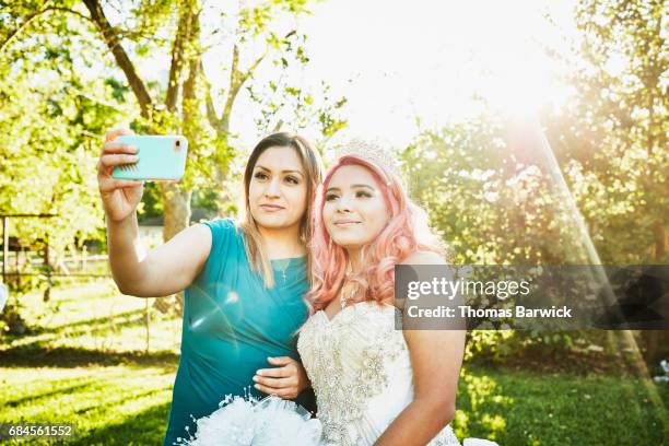 mother taking selfie with daughter dressed in quinceanera gown in backyard - quinceanera - fotografias e filmes do acervo