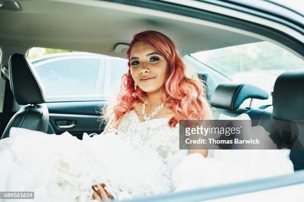 smiling young woman in quinceanera gown sitting in back seat of car - nosotroscollection stockfoto's en -beelden