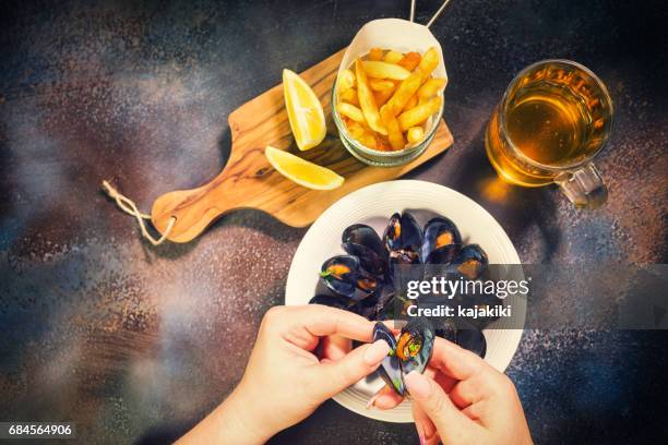 young women eating freshly steamed mussels dish - mussels stock pictures, royalty-free photos & images