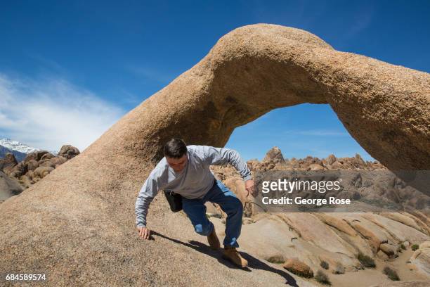 Man climb around Mobius Arch on April 4 near Lone Pine, California. Owens Valley is an arid valley in eastern California, to the east of the Sierra...