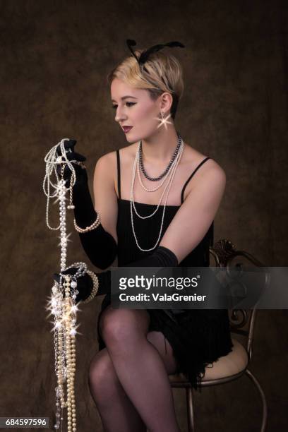 elegant young blonde woman in 1920s era outfit, three quarter length sitting. - 1920s flapper girl stock pictures, royalty-free photos & images