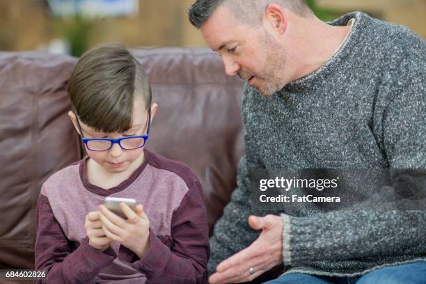 father looks at son on the phone - parental control stock pictures, royalty-free photos & images