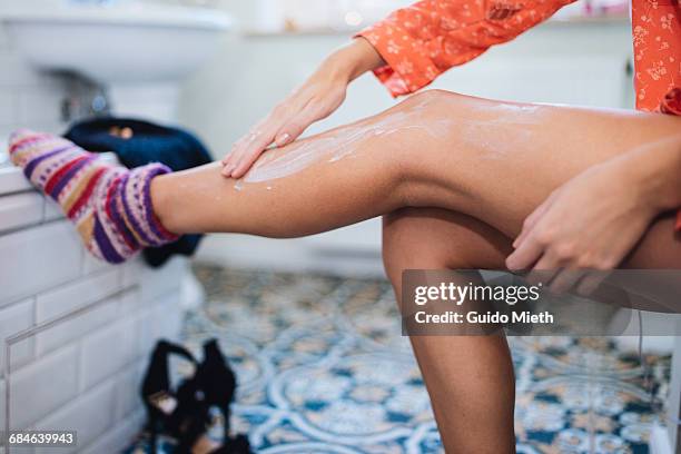 woman putting lotion on her leg. - partie inférieure photos et images de collection