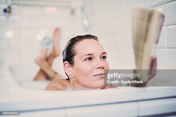 woman reading in bathtube. - woman bath tub wet hair stock pictures, royalty-free photos & images