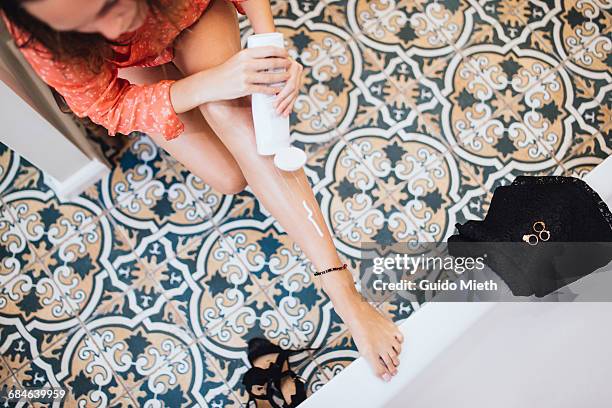 woman putting lotion on her leg. - woman holding legs fotografías e imágenes de stock