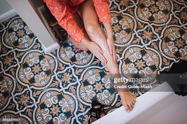 woman putting lotion on her leg. - partie inférieure photos et images de collection