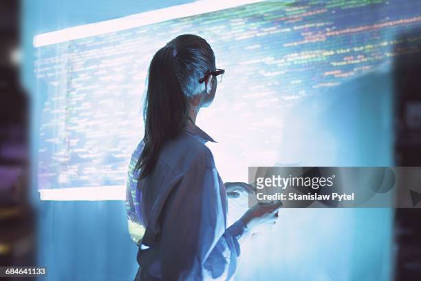 woman looking at wall with code - woman coding foto e immagini stock