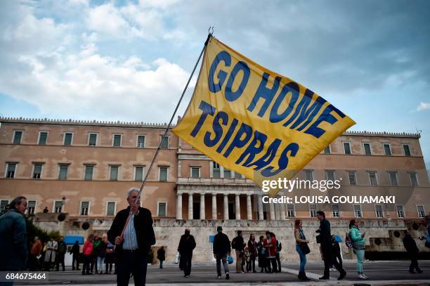 Man holds a flag reading 'Go home Tsipras' outside the Greek parliament in Athens on May 18 during a demonstration on the sidelines of a voting on...