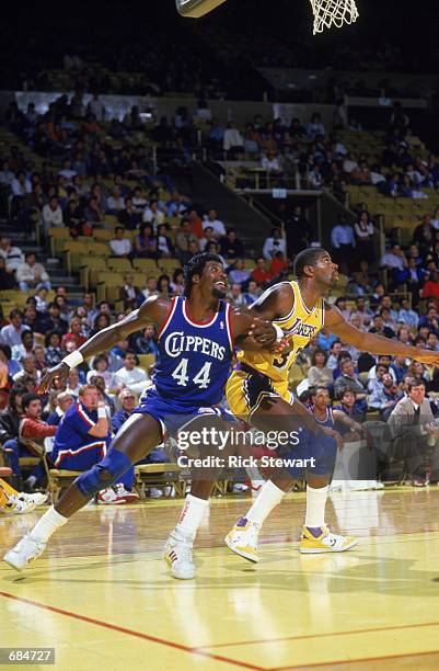 Michael Cage of the Los Angeles Clippers and Magic Johnson of the Los Angeles Lakers attempt to rebound the ball, during the NBA game at the Great...