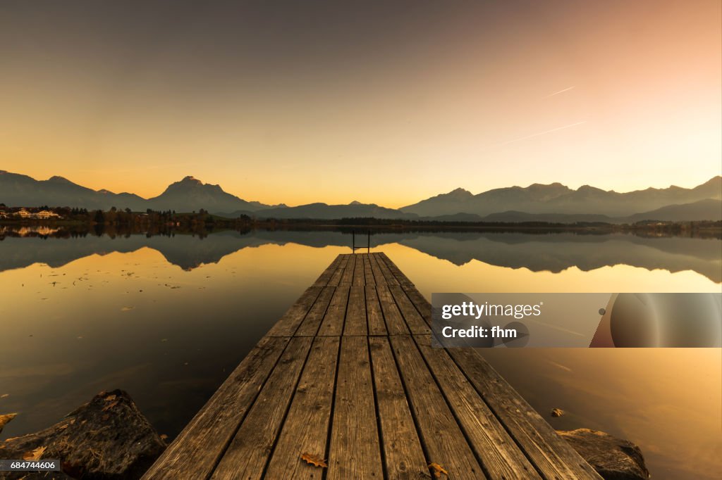 Lake Hopfen with a jetty and Alps mountains with idyllic sunset (Allgäu/ Bavaria/ Germany)