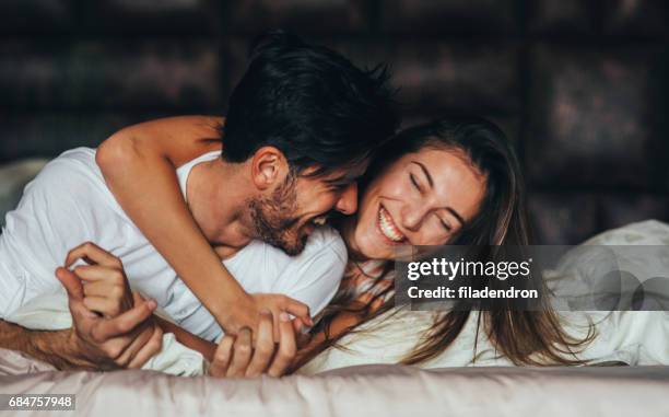 heureux jeune couple au lit - rollup photos et images de collection