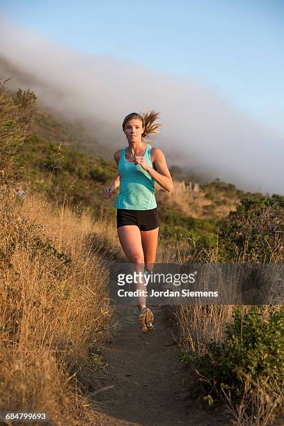 running in san francisco - young blonde woman facing away photos et images de collection