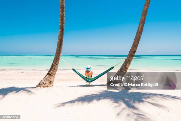 caucasian woman lying on hammock on a tropical beach. - idyllisch stockfoto's en -beelden