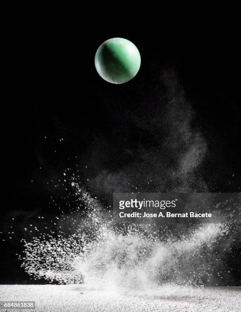 Impact and rebound of a ball   on a surface of land and powder on a black background