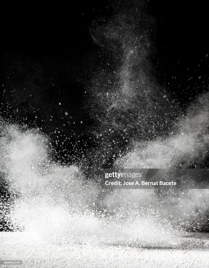 Explosion of a cloud of powder of particles of color white  and a black background