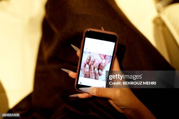 In this picture taken on January 7, 2017 a Japanese woman checks nail designs on a smartphone as she gets a manicure at a nail saloon in Tokyo. -...