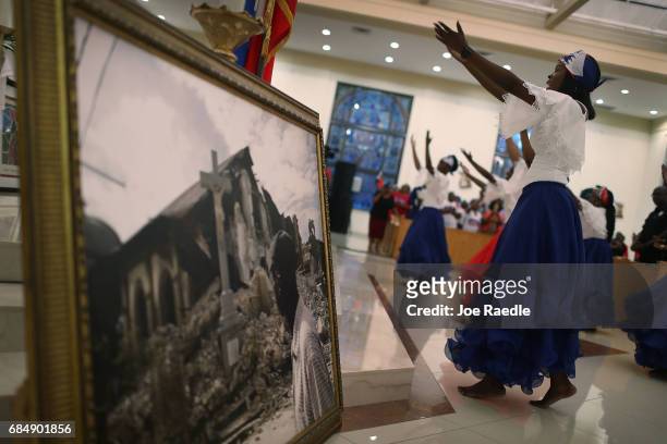Hermonde Alcenat takes part in a dance near a framed picture of a church that was destroyed by the massive 2010 Earthquake in Haiti during a service...