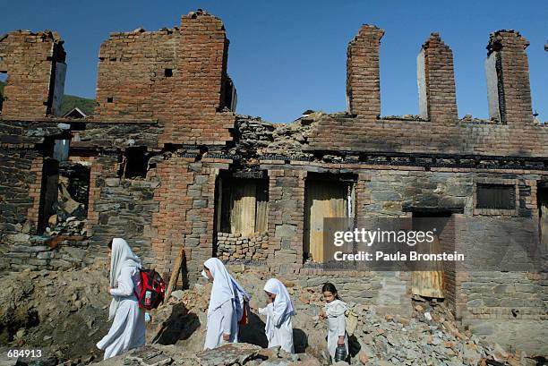 Students walk home past burned homes June 10, 2002 in Baramulla, Kashmir, India. The houses were destroyed by the Indian Army during a raid looking...