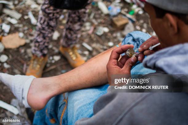 Man loads a syringe near near a heroin encampmentin the Kensington neighborhood of Philadelphia, Pennsylvania, on April 14, 2017. In North...